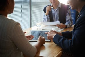 Group of positive entrepreneurs discussing digital marketing strategy at meeting in coffeeshop